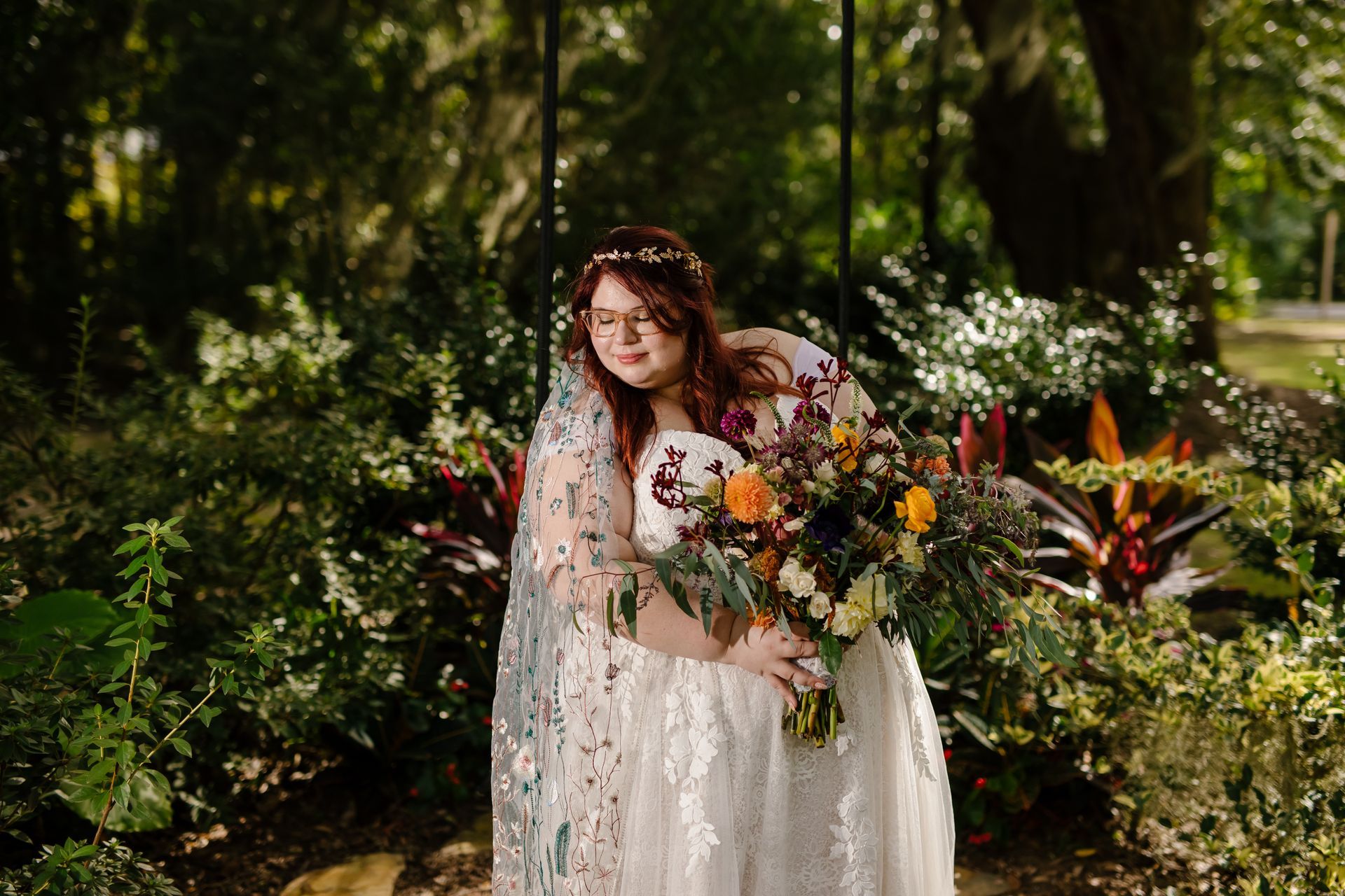 Woman in a white dress holding a colorful bouquet in a lush garden setting