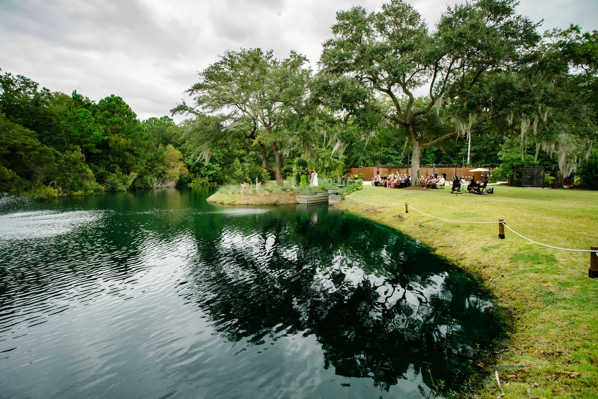 Serene park pond with trees reflecting in the water and people sitting on the grassy shore