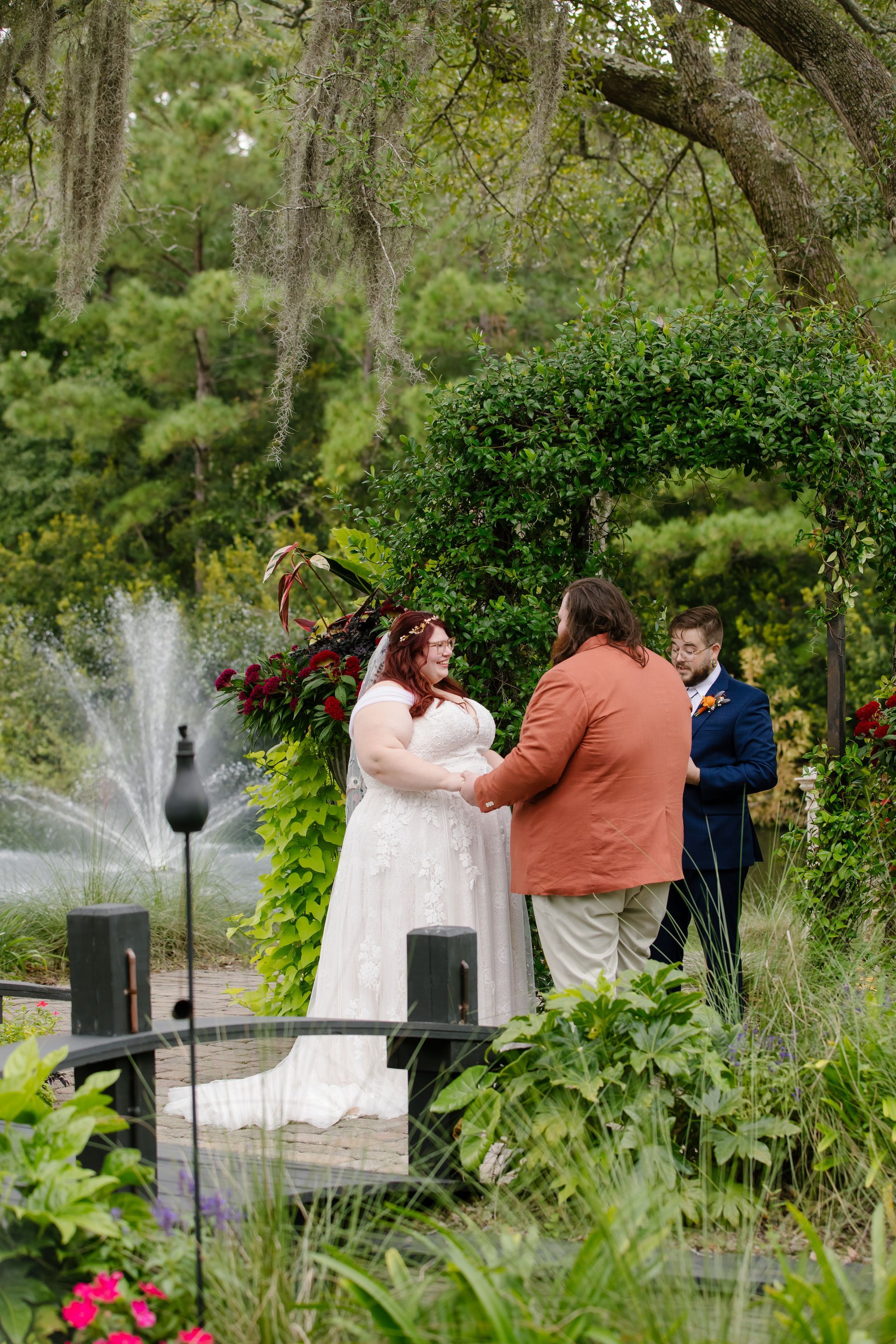 Outdoor wedding ceremony beside a fountain, with a couple exchanging vows in a garden.