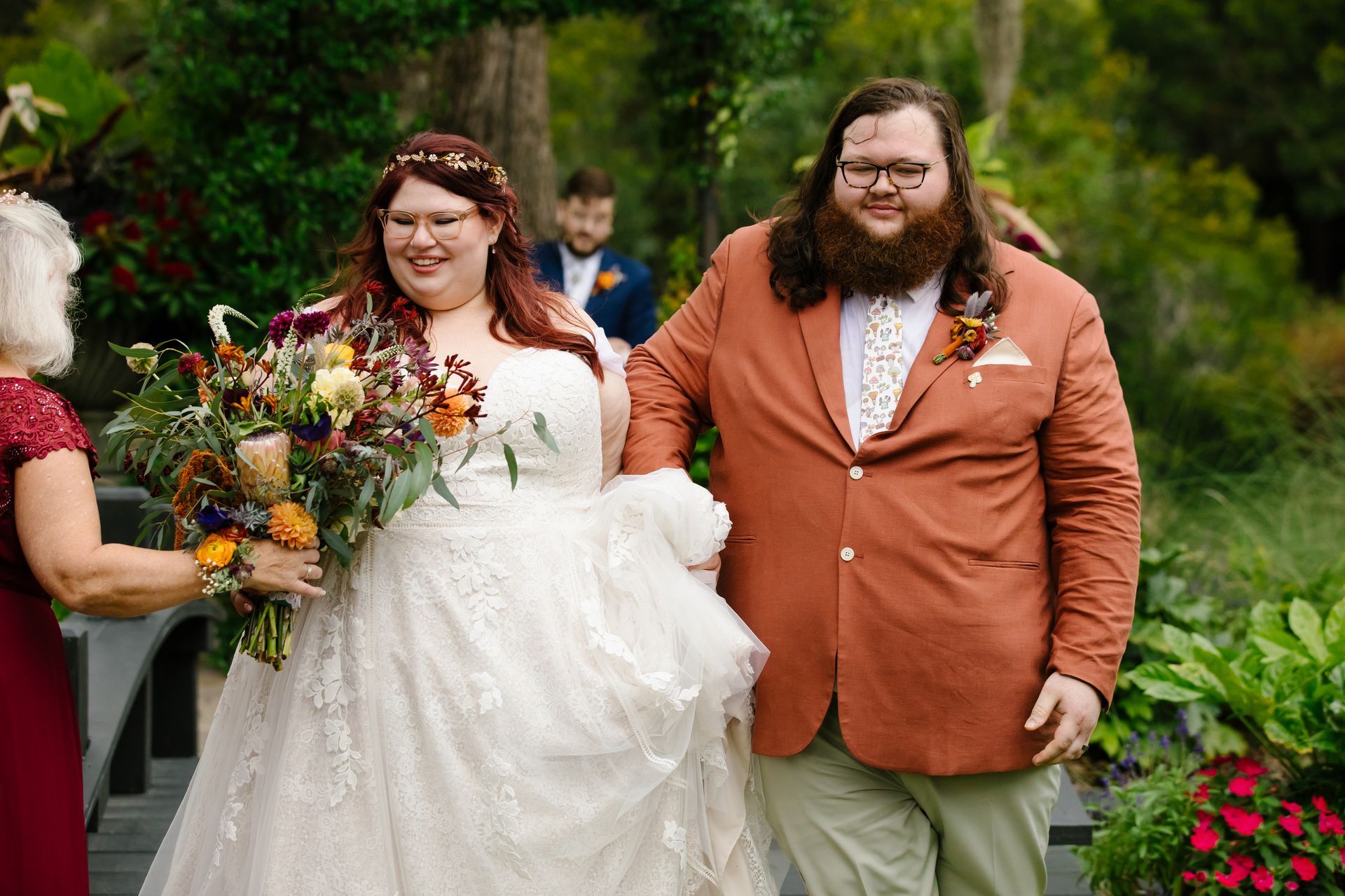 Bride and groom walking outdoors, bride holding bouquet, in a garden setting