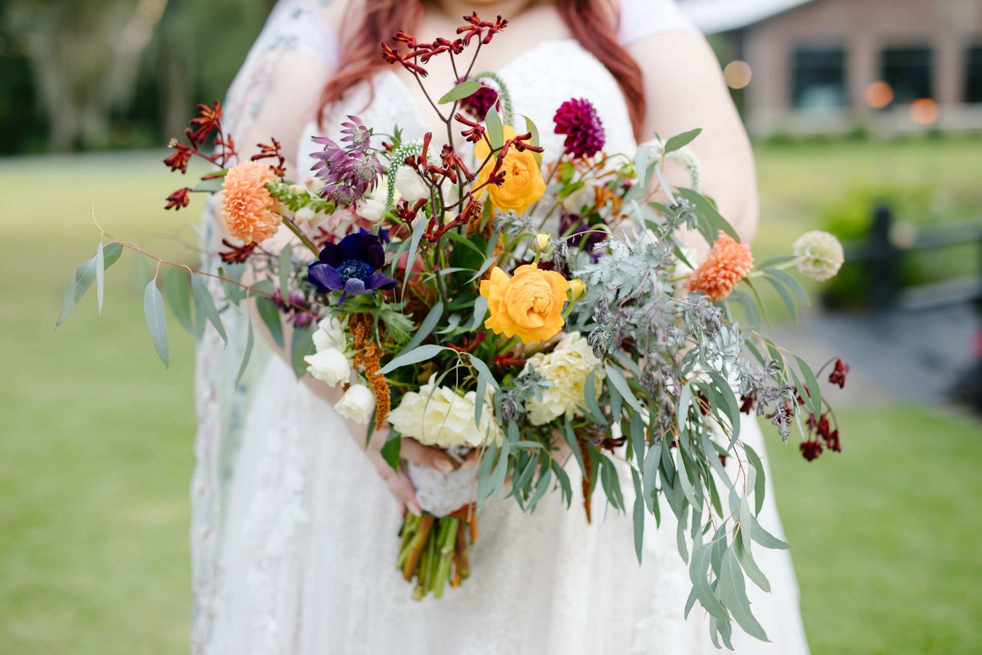 Bride holding a colorful bouquet of wildflowers and roses in a garden setting