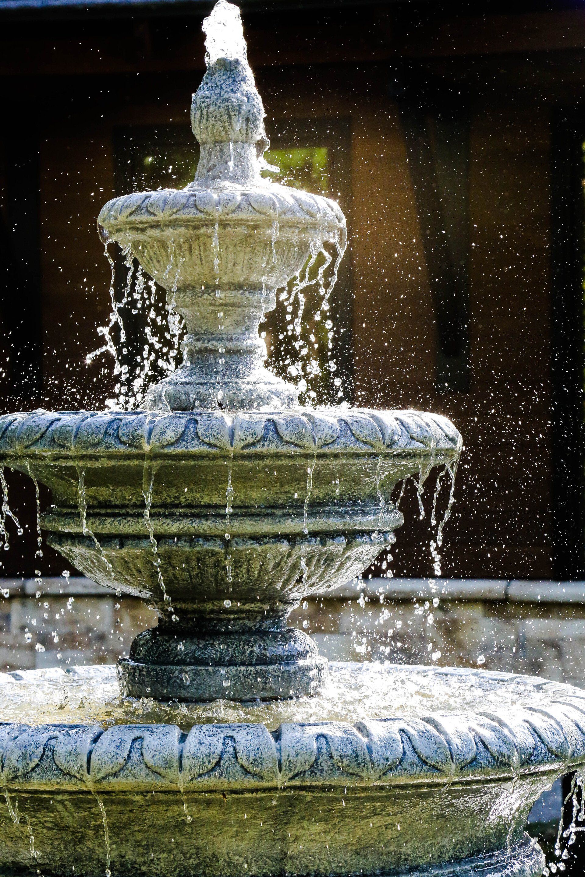 Tiered stone fountain splashing water in a garden setting