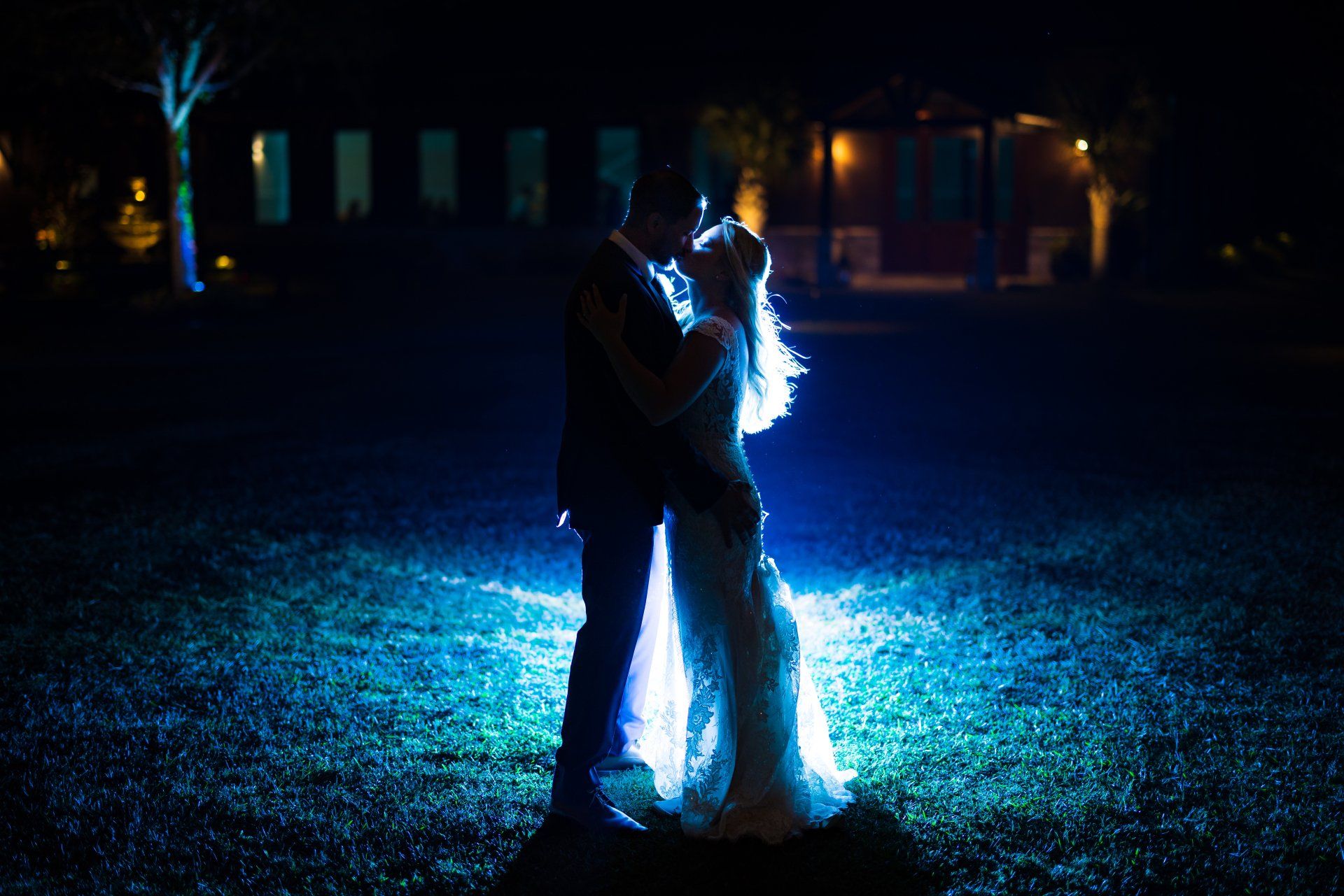 Two people embracing at night, surrounded by bright blue flames on the ground