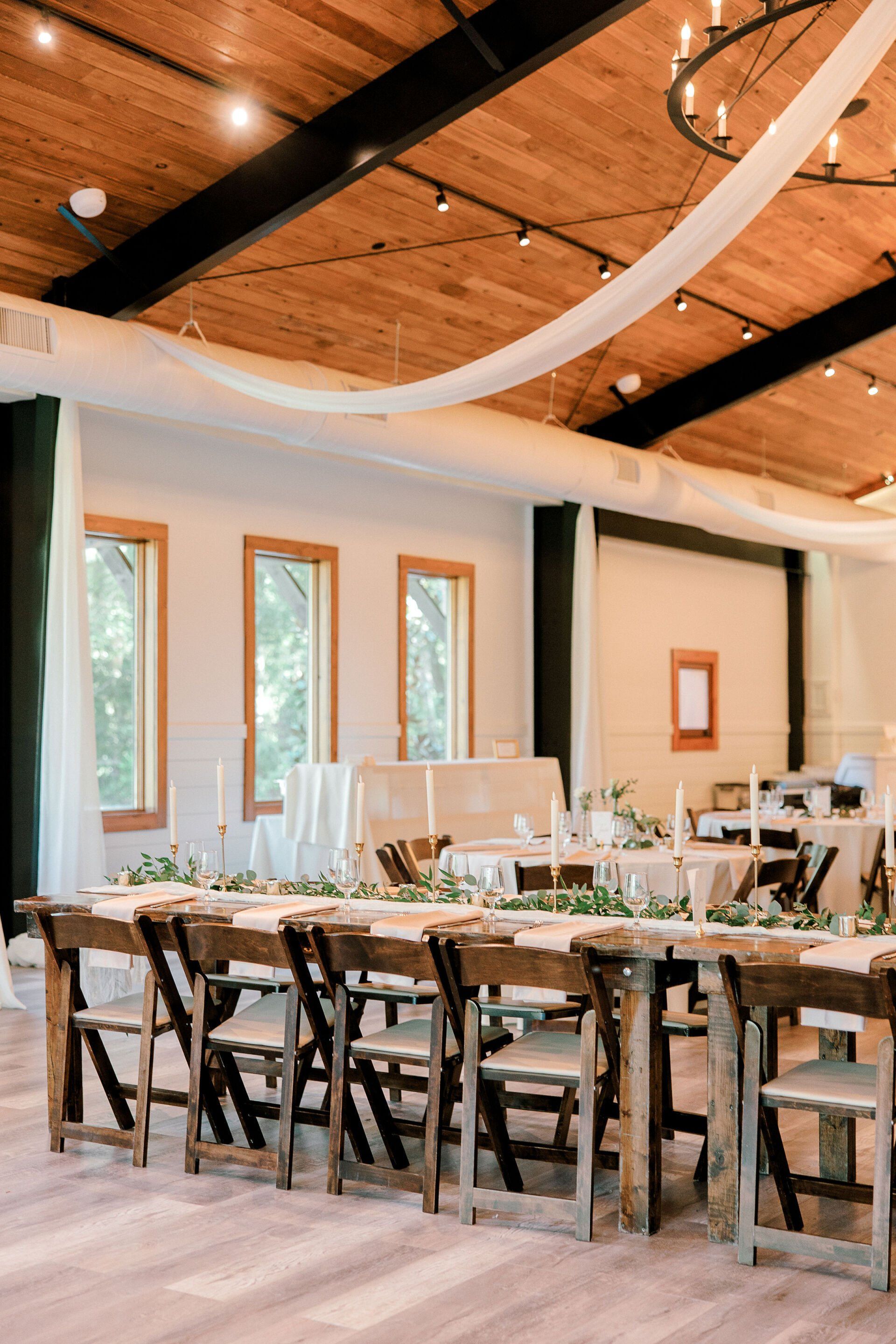 Elegant dining room with long wooden table, rustic chairs, and draped white fabric ceiling
