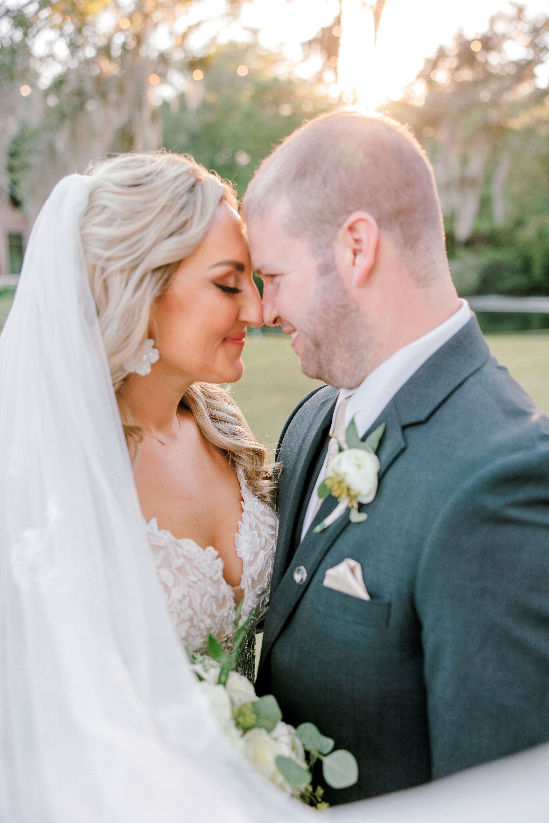 Bride and groom touching foreheads outdoors at sunset, in a close wedding portrait