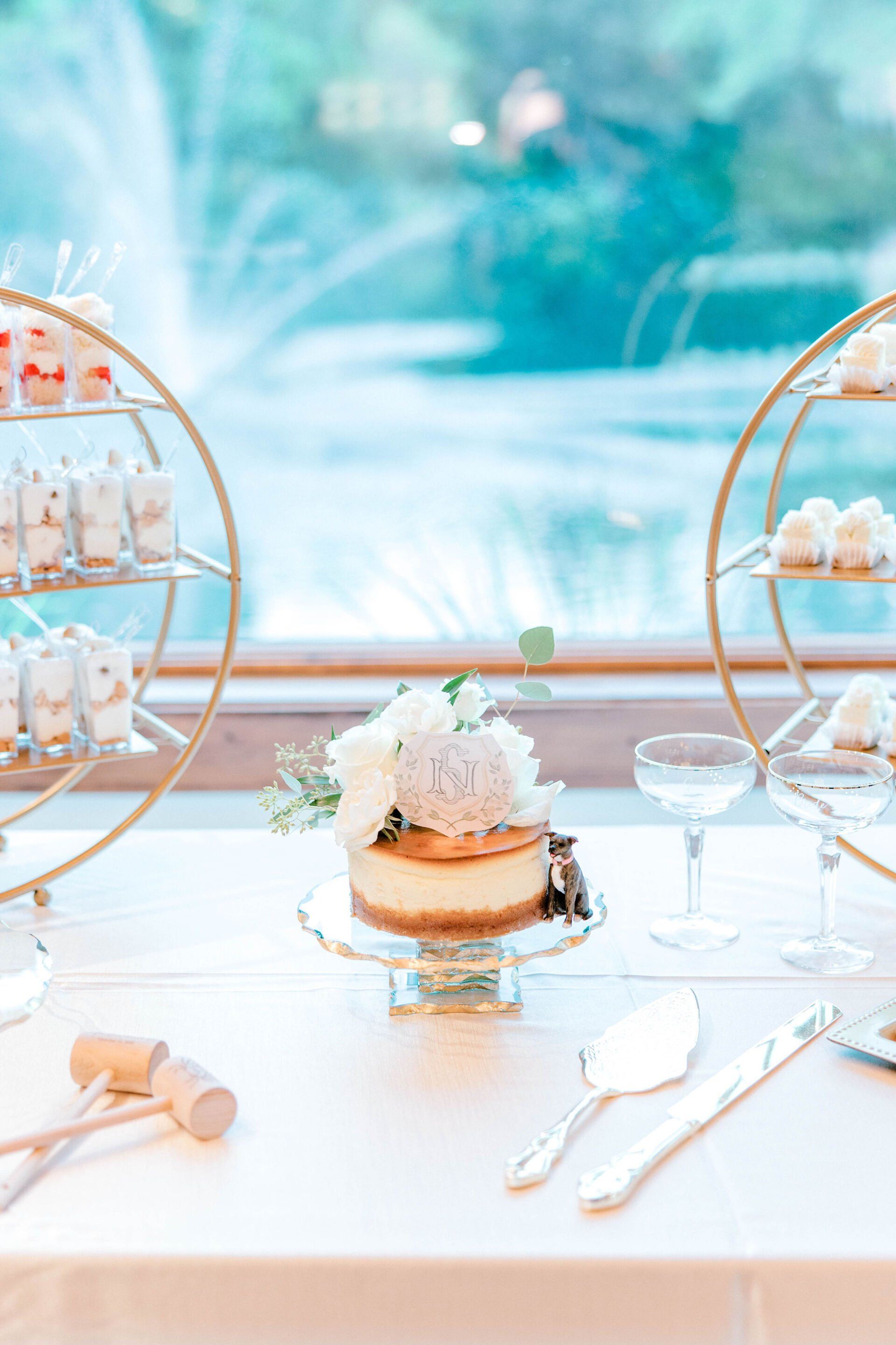 Elegant dessert table with a small cake, white florals, and gold display stands by a bright window