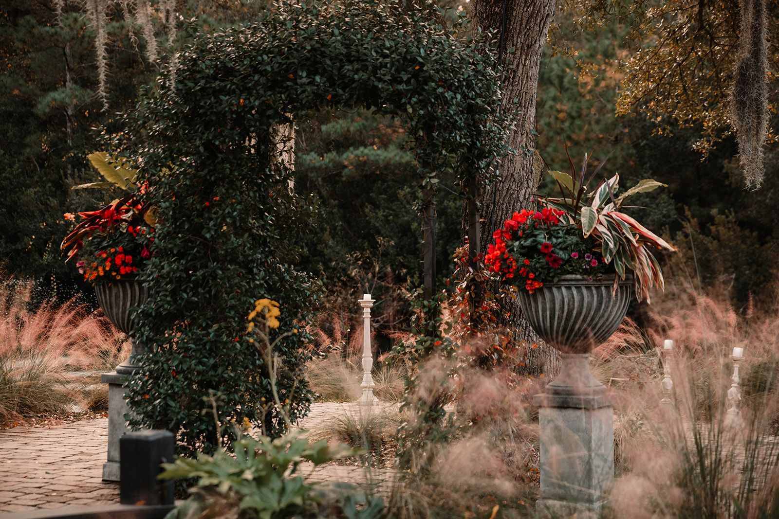 Outdoor holiday wreaths with red flowers on stone posts in a garden