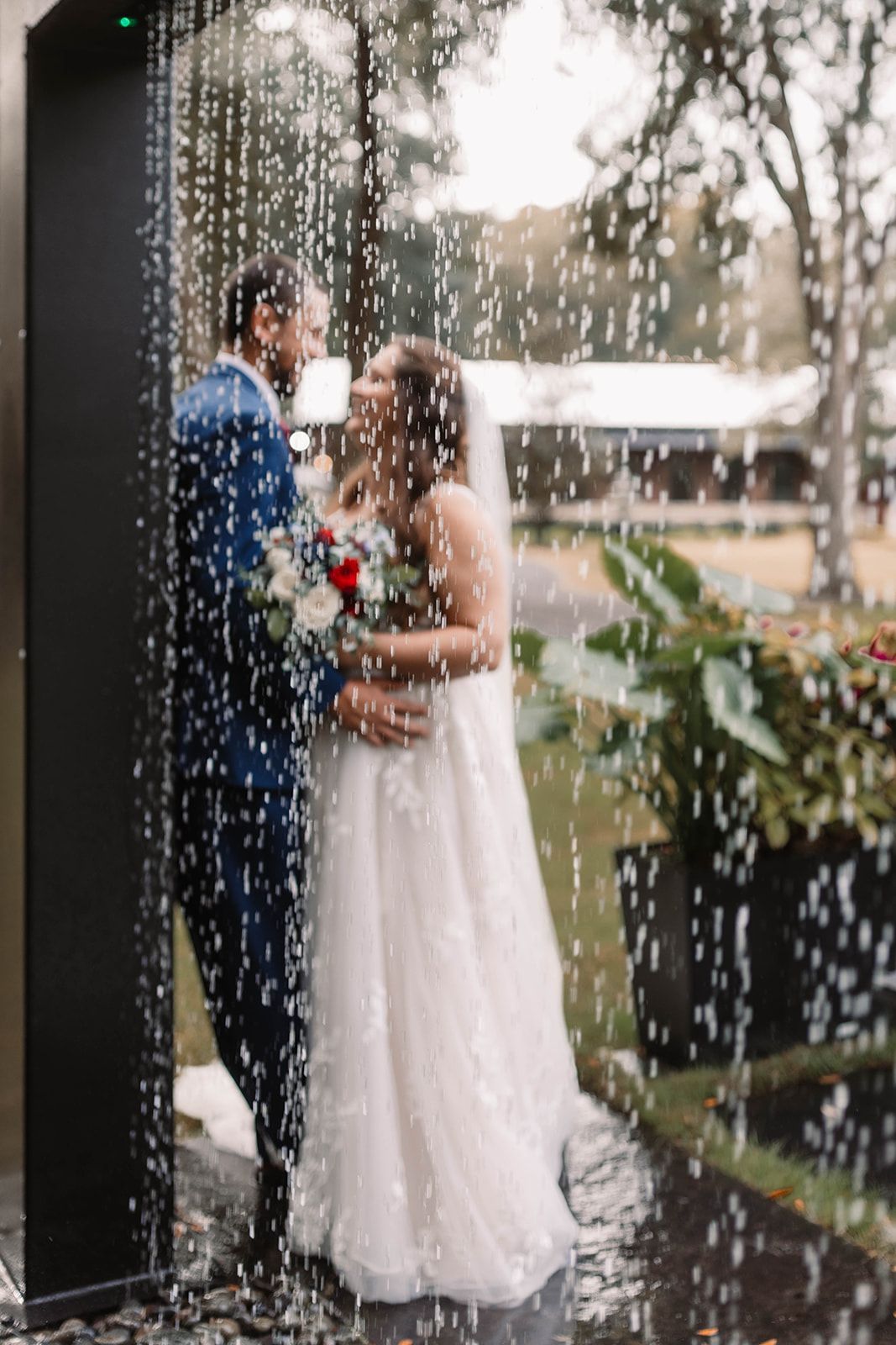 Bride and groom embracing under falling rain on a wedding porch
