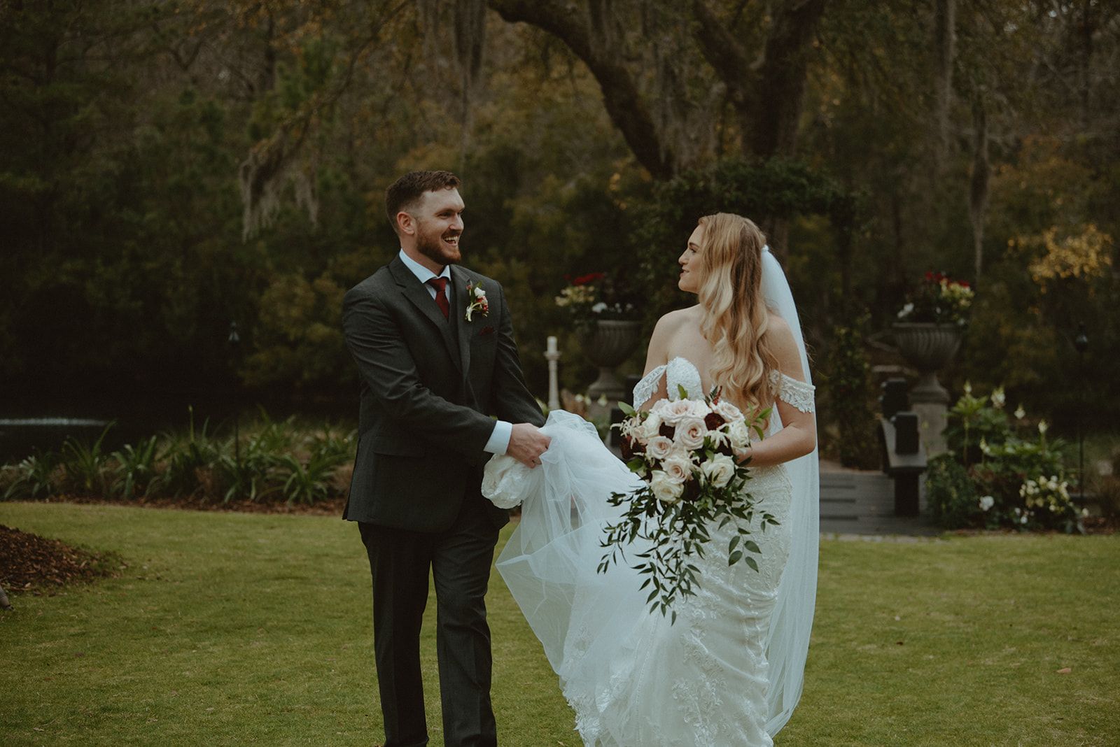 Bride and groom in a garden, smiling and holding a bouquet during their wedding ceremony