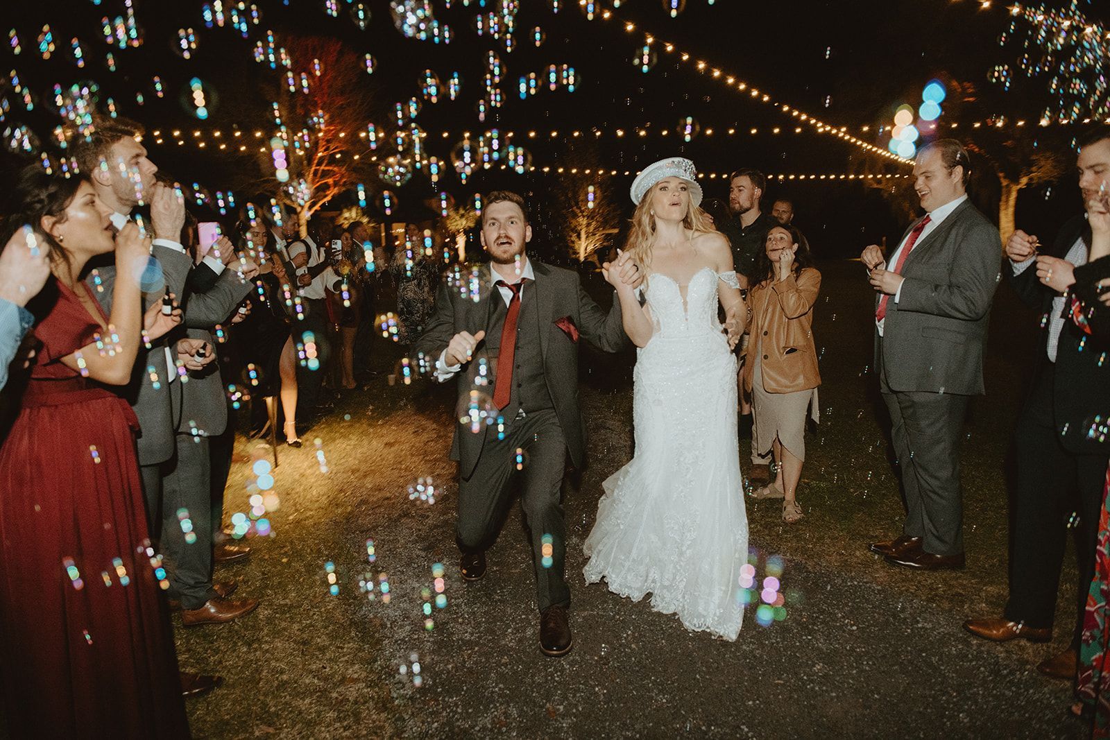 Wedding couple walking through a sparkler send-off with guests at night