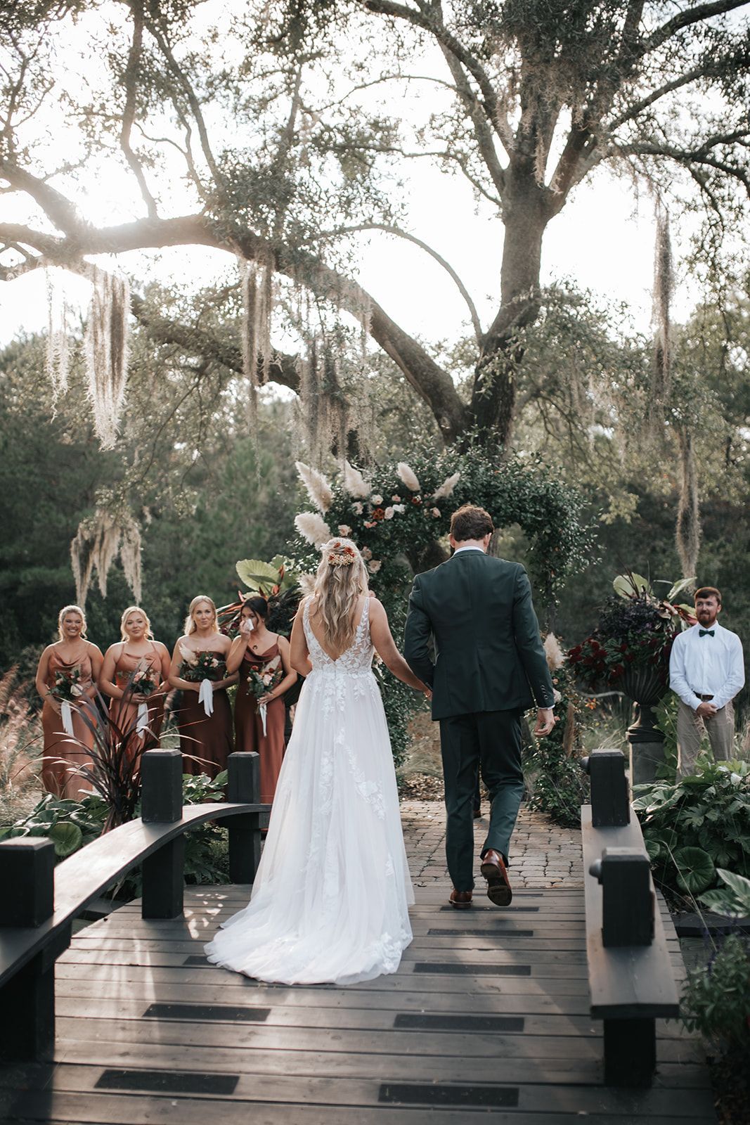 Bride and groom walk down a wooden aisle at an outdoor wedding ceremony