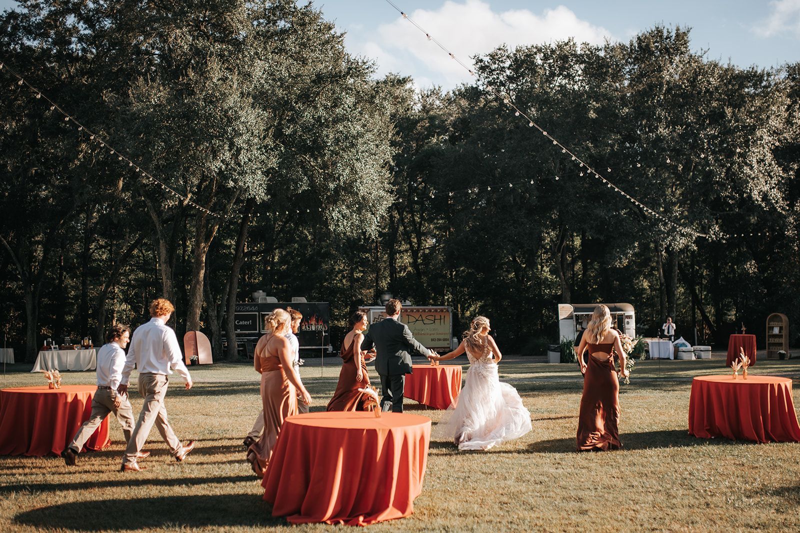 People mingling around red tablecloth-covered cocktail tables at an outdoor garden event