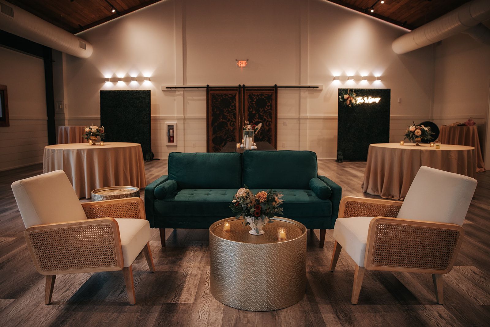 Elegant lounge with teal sofa, white chairs, and gold tables in a softly lit hall