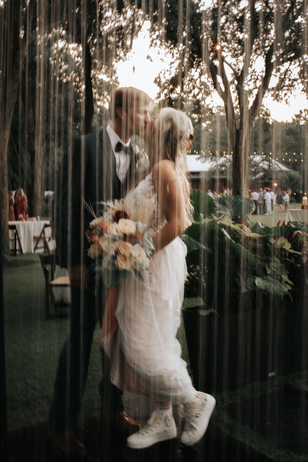 Bride and groom kissing under a curtain of water with city lights in the background