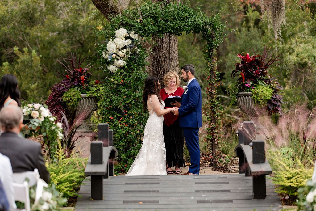 Wedding couple exchanging vows under a floral arch in a garden ceremony