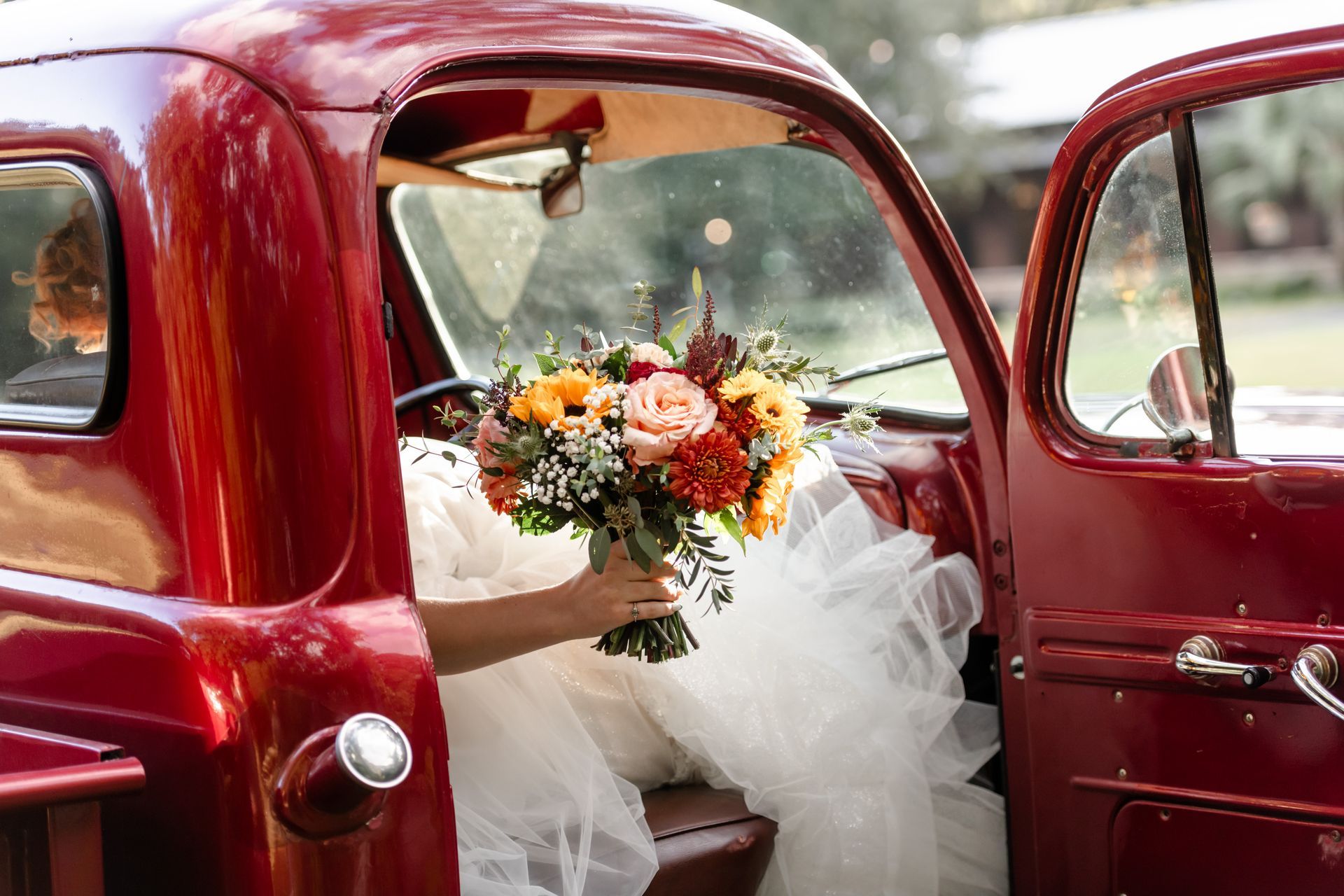 Bouquet of flowers in a red vintage car decorated for a wedding, with white tulle inside.