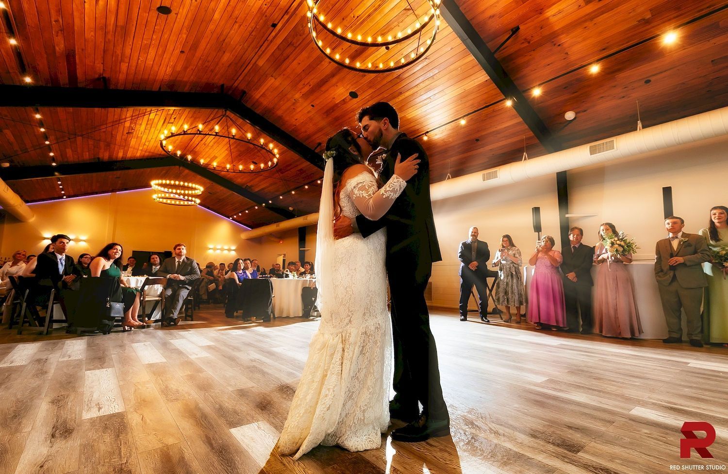 Couple slow dancing in a warmly lit banquet hall during a formal celebration