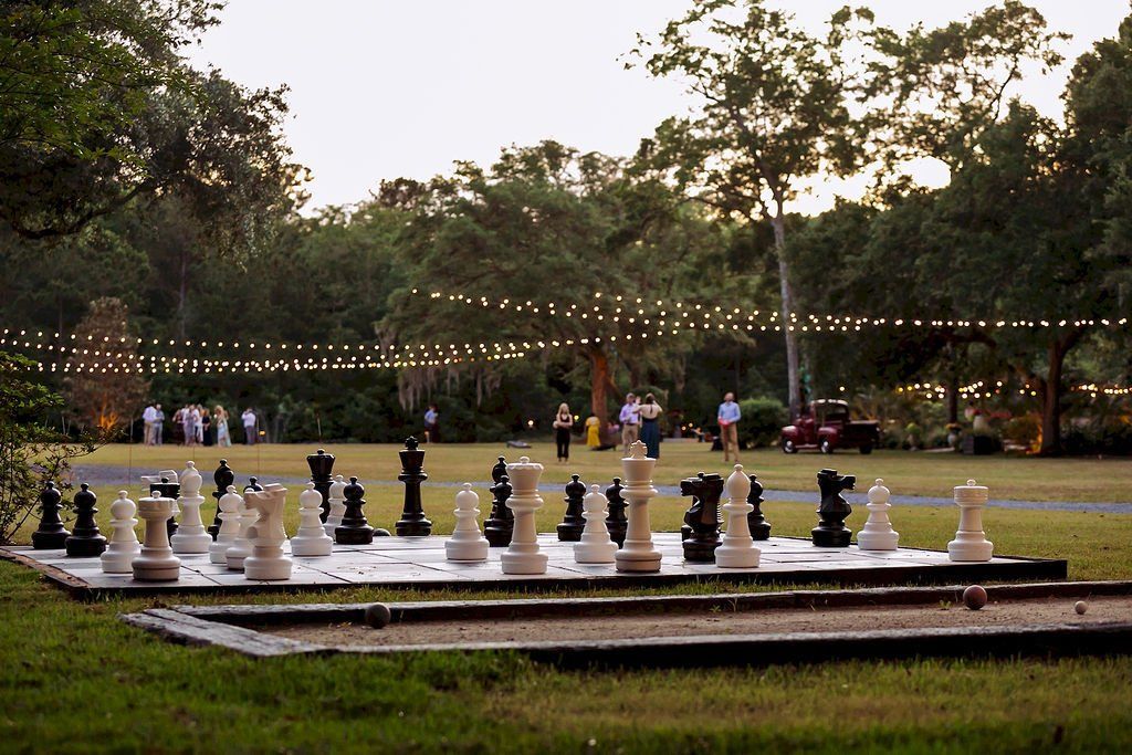Outdoor chess board with oversized black and white pieces in a park at dusk