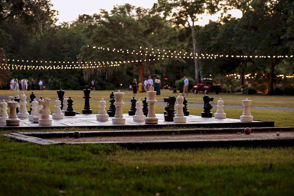 Outdoor giant chessboard with oversized black and white pieces in a park at dusk