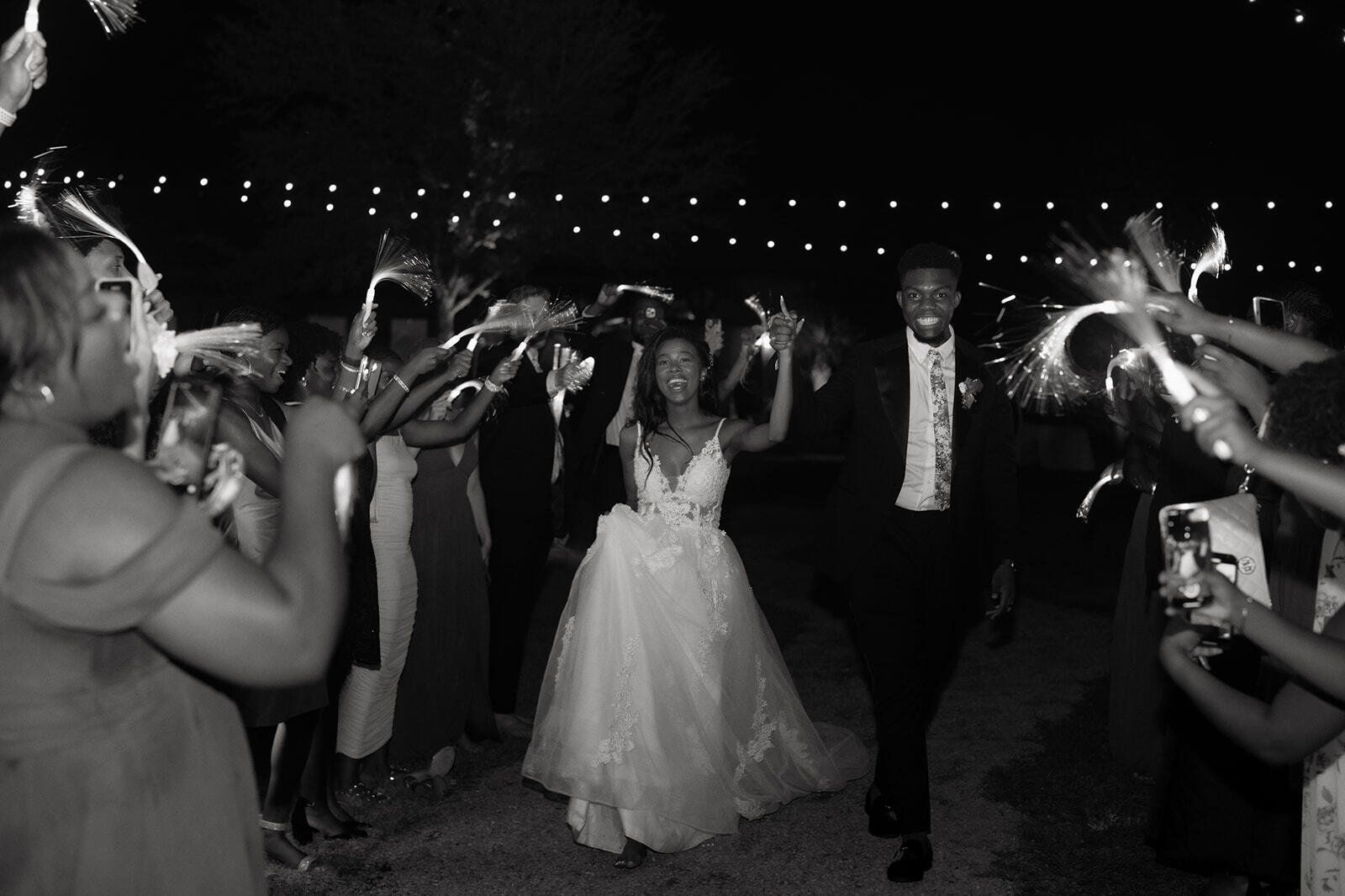 Wedding couple walking through a sparkler send-off at night, guests lining the aisle