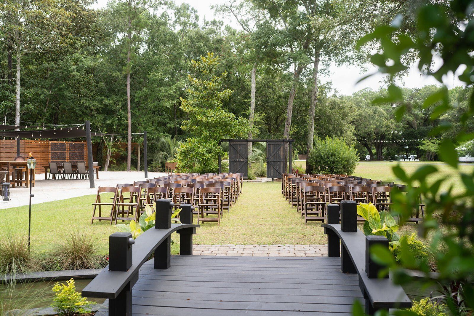 Outdoor wedding ceremony setup with rows of chairs on a grassy aisle and a wooden deck in the foreground