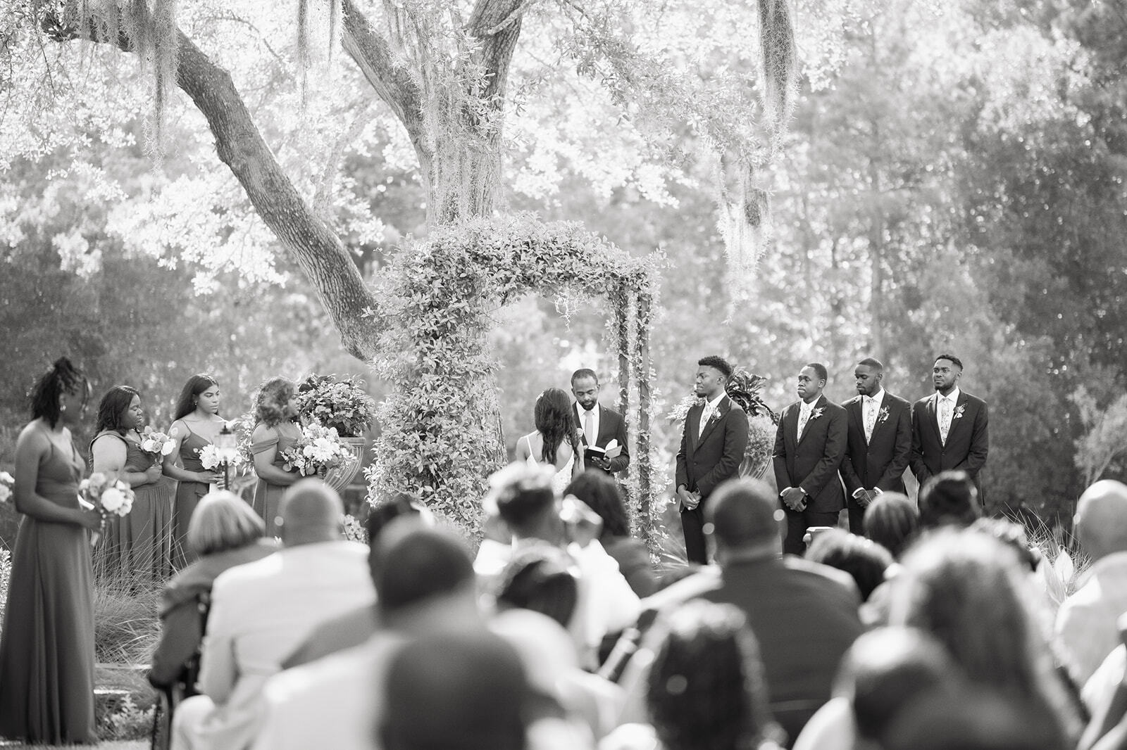 Outdoor wedding ceremony with couple standing before guests beneath trees