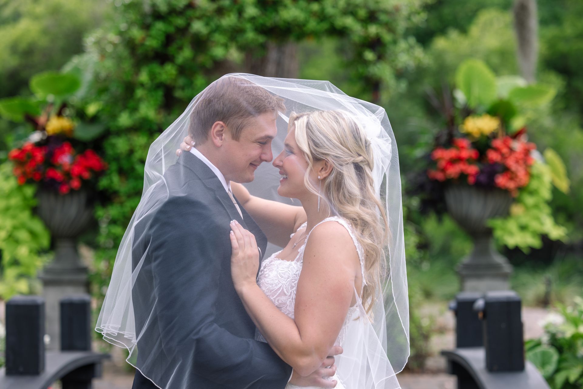 Bride and groom in wedding attire sharing an intimate moment in a garden setting