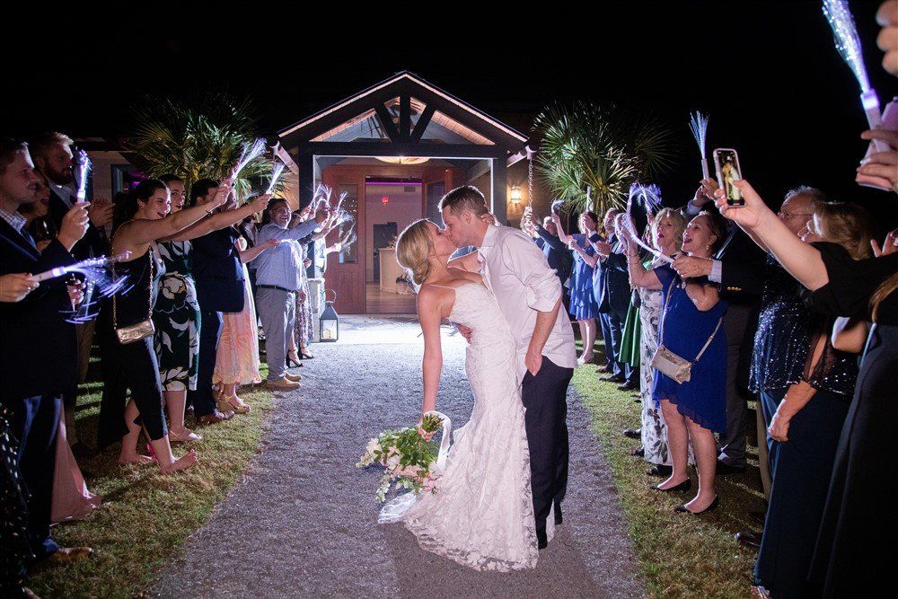 Bride and groom kiss under sparklers outside a lit chapel at night