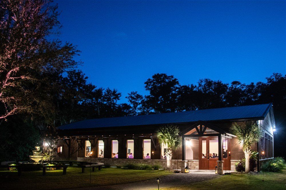 Lit building at night with warm lights, set among trees and benches under a deep blue sky