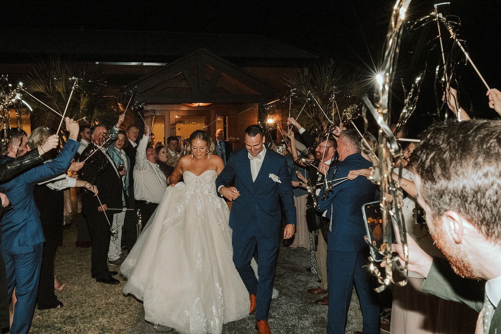 Bride and groom walking through a sparkler tunnel at a nighttime wedding reception