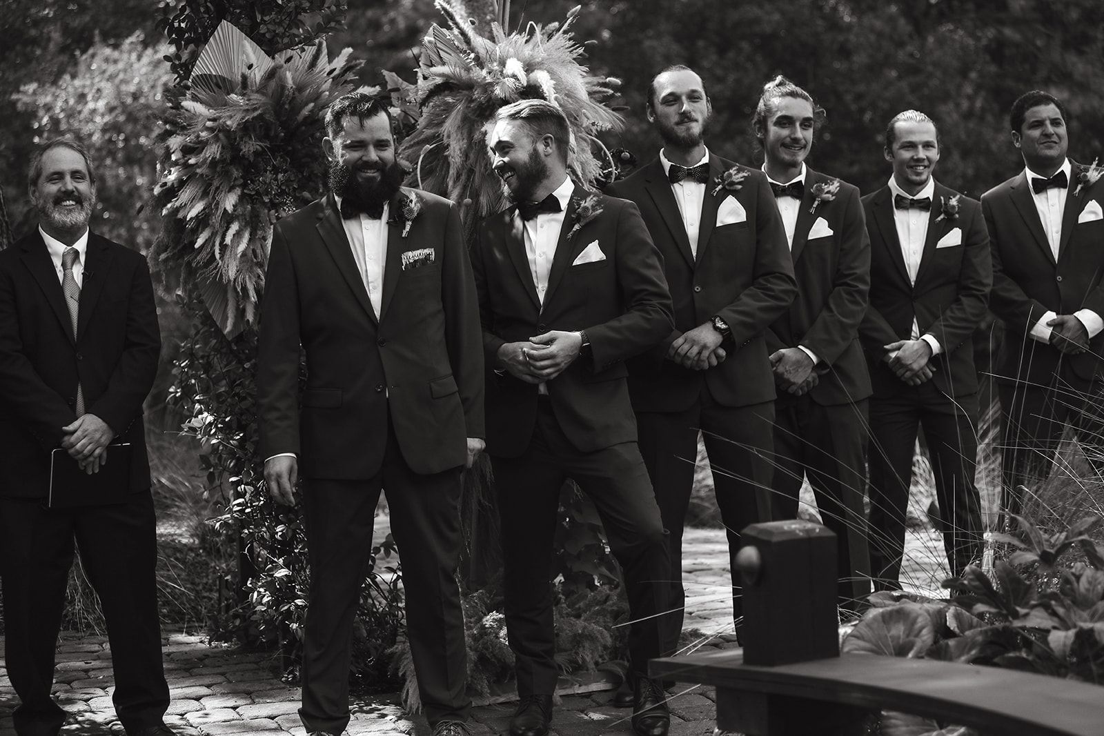 Group of men in suits posing outdoors with palm trees in the background