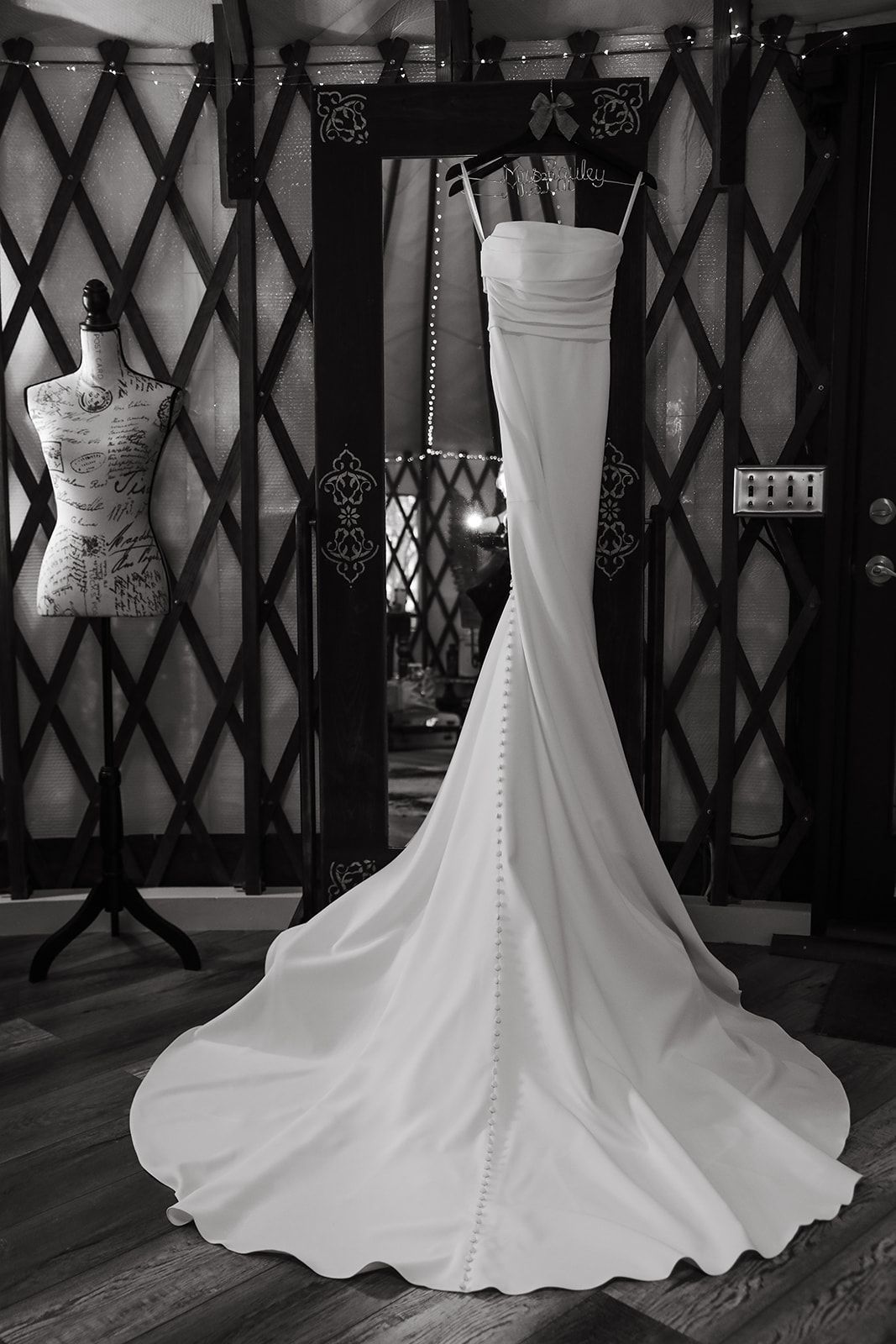 White strapless mermaid wedding gown with a long train displayed on a mannequin in a boutique window.