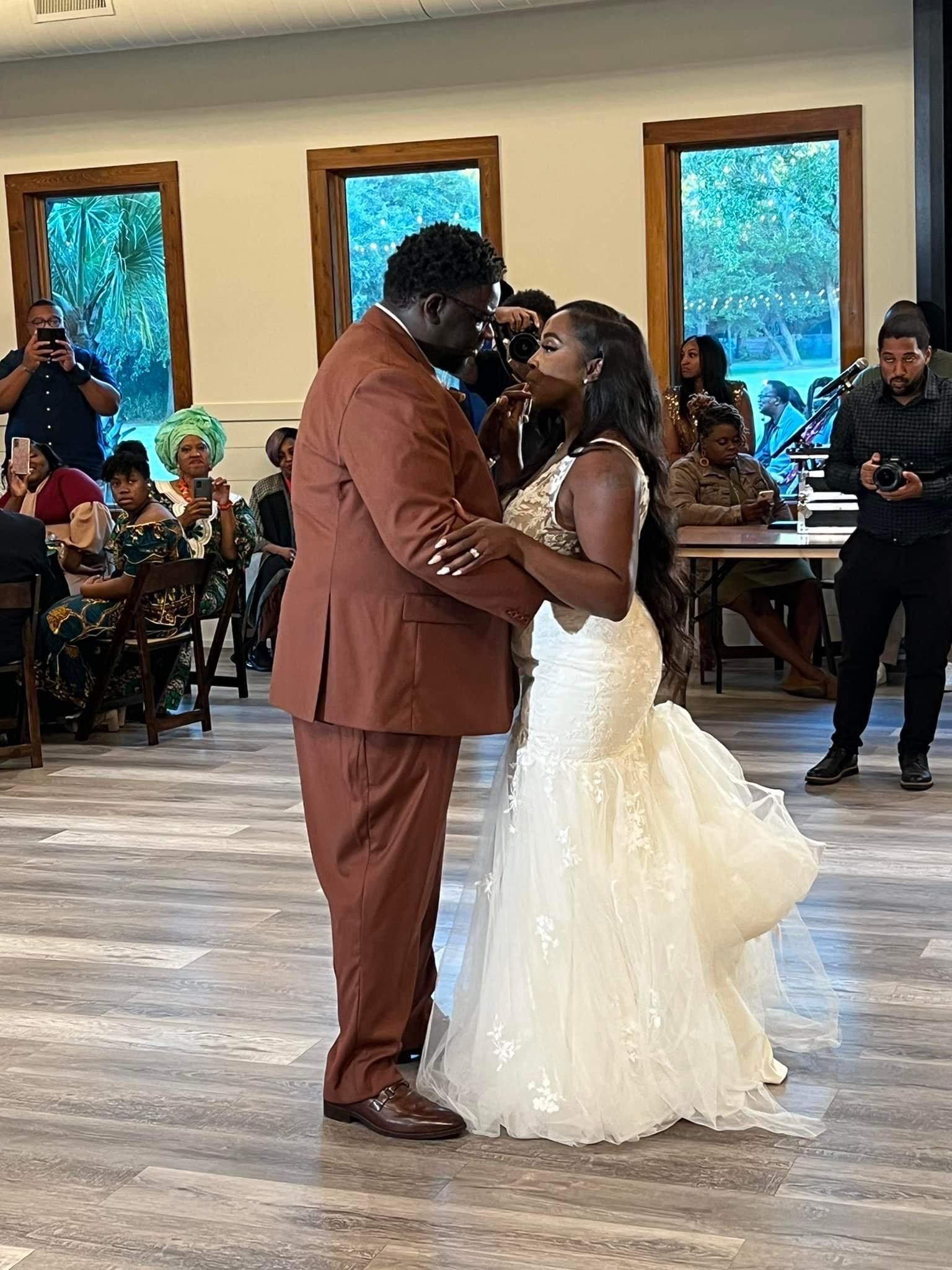 Bride and groom kissing during a wedding reception in a bright hall with seated guests