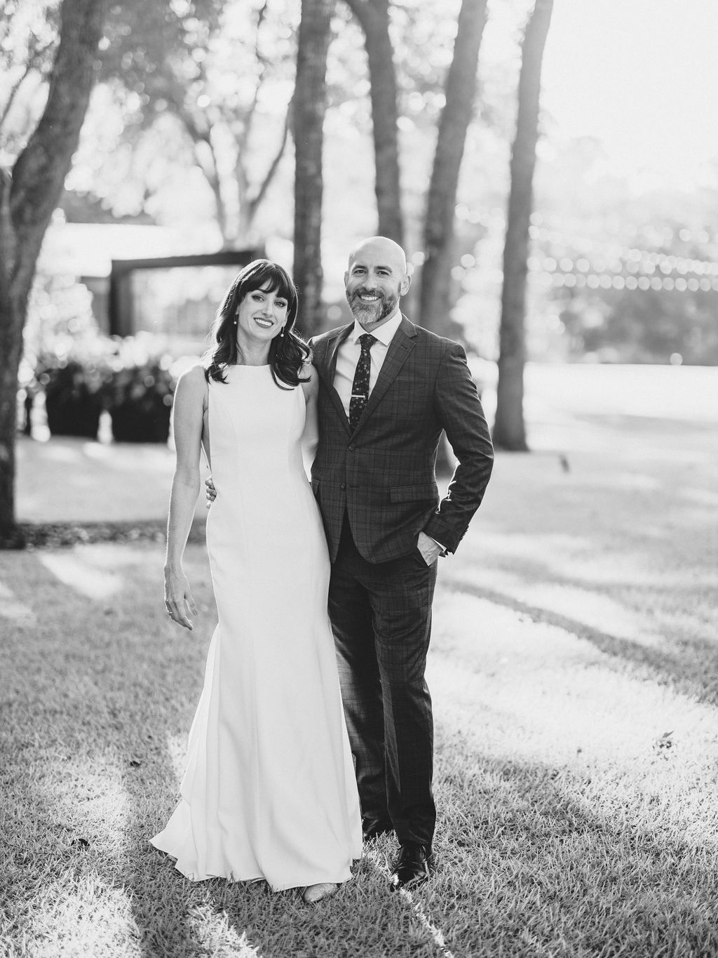 Bride and groom standing together outdoors in a black-and-white wedding portrait