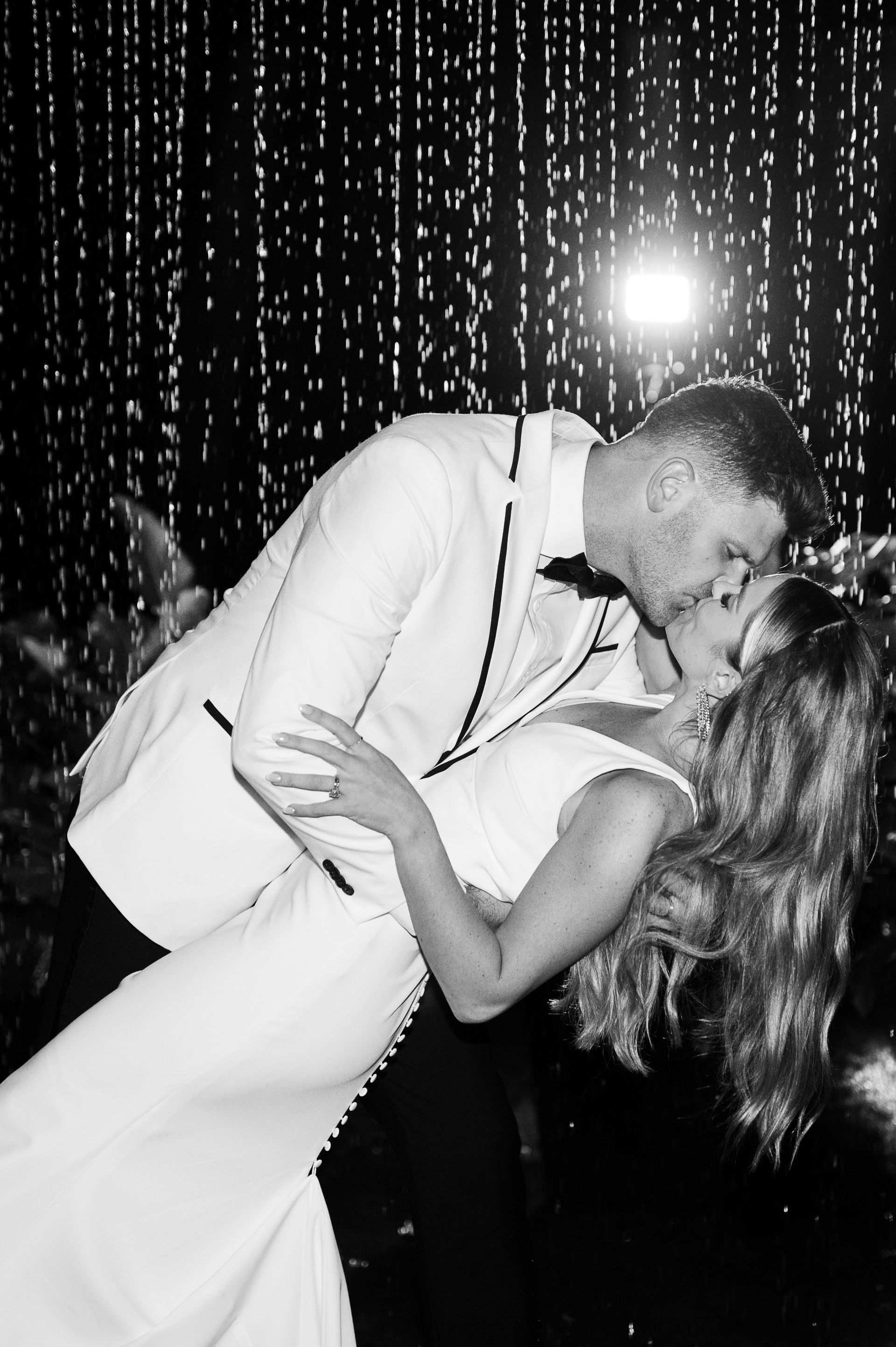 Couple kissing on a dance floor, with sparkling lights in the background.