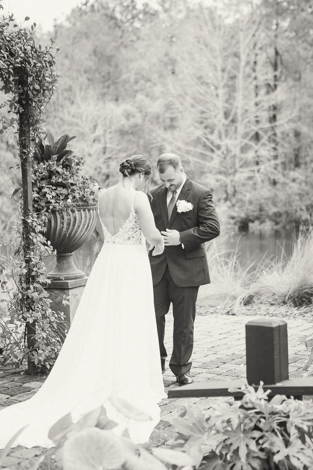 Bride and groom standing outdoors in a garden, facing each other during their wedding ceremony.