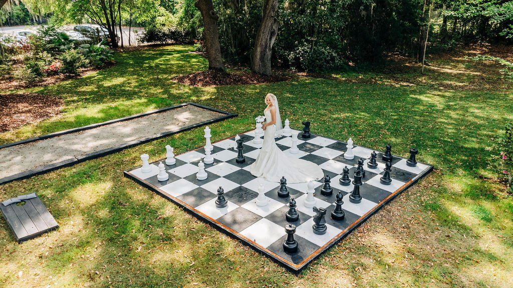 Outdoor giant chessboard on grass with oversized pieces and a person standing near the center