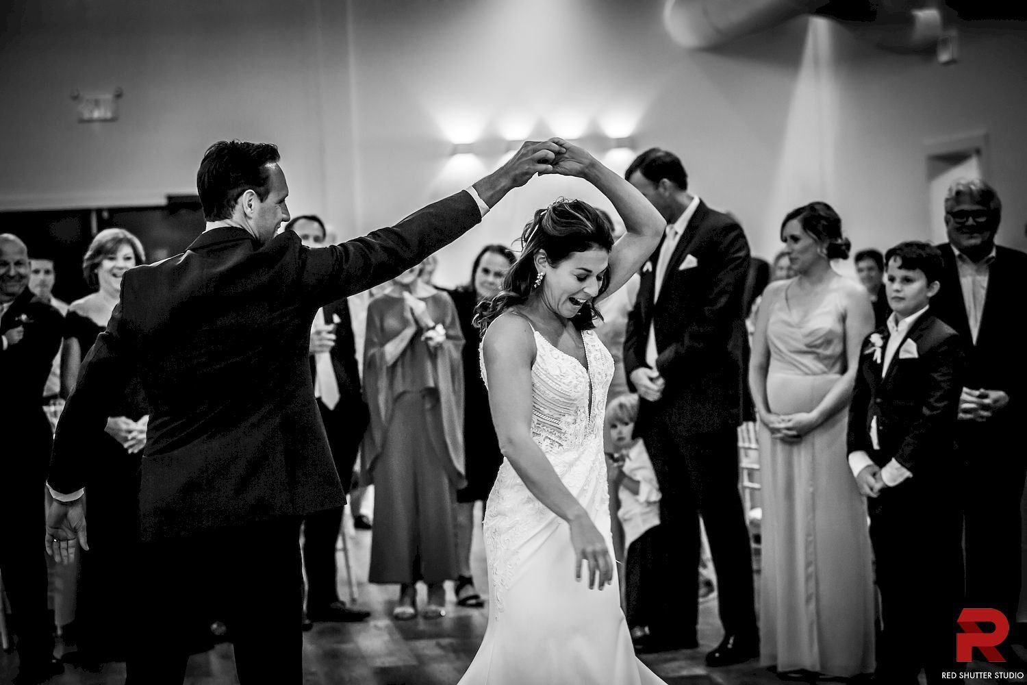 Wedding couple under raised arms of guests in a black-and-white dance scene