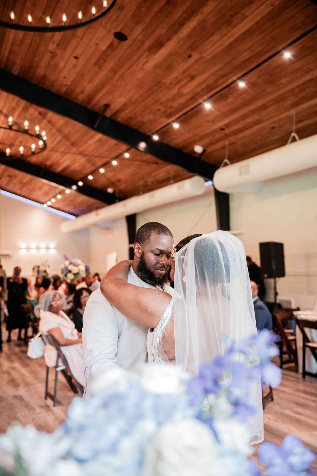 Bride and groom embracing during a wedding ceremony in a wood-paneled hall