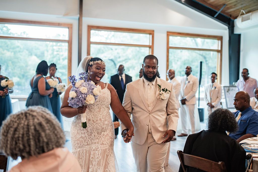 Bridal couple walking down the aisle in a bright indoor wedding venue, guests seated nearby