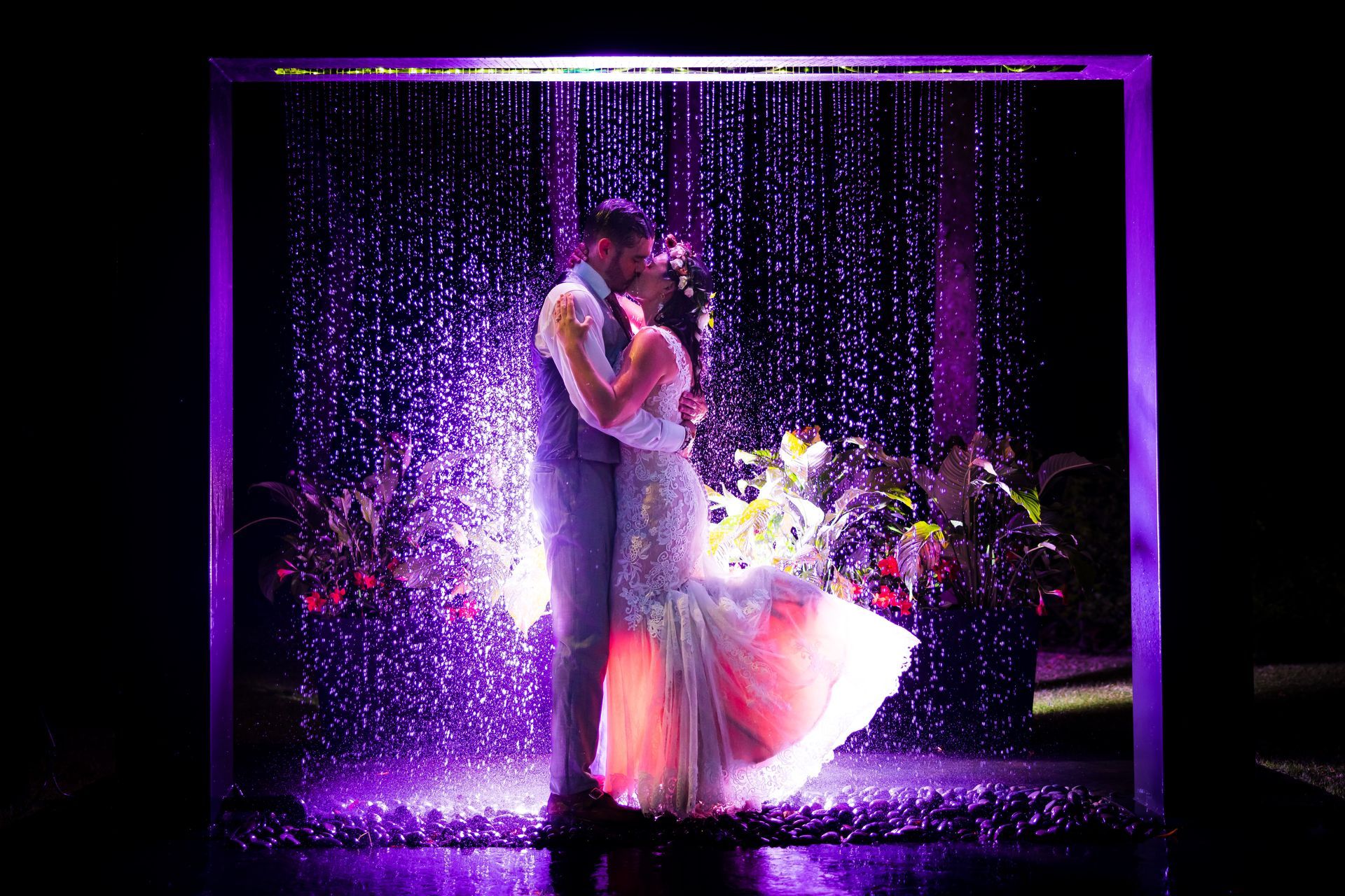 Couple dancing under purple lights and sparkling confetti on a dark stage