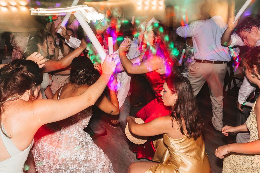 People dancing at a colorful party with bright lights and raised arms