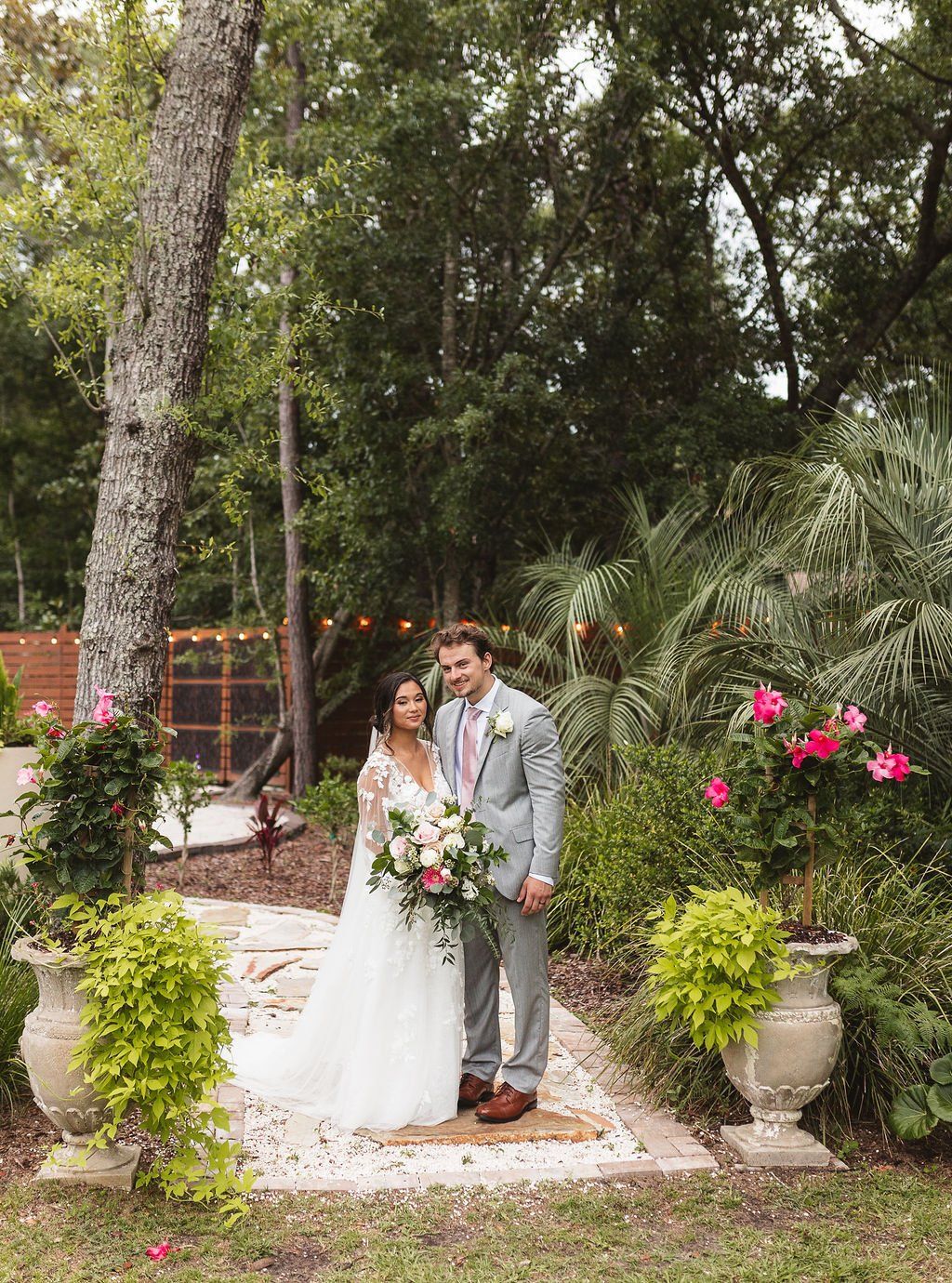 Bride and groom standing together in a garden wedding setting with flowers and greenery