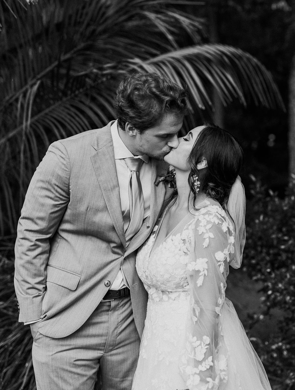 Black-and-white couple kissing outdoors, the man in a suit and the woman in a lace dress