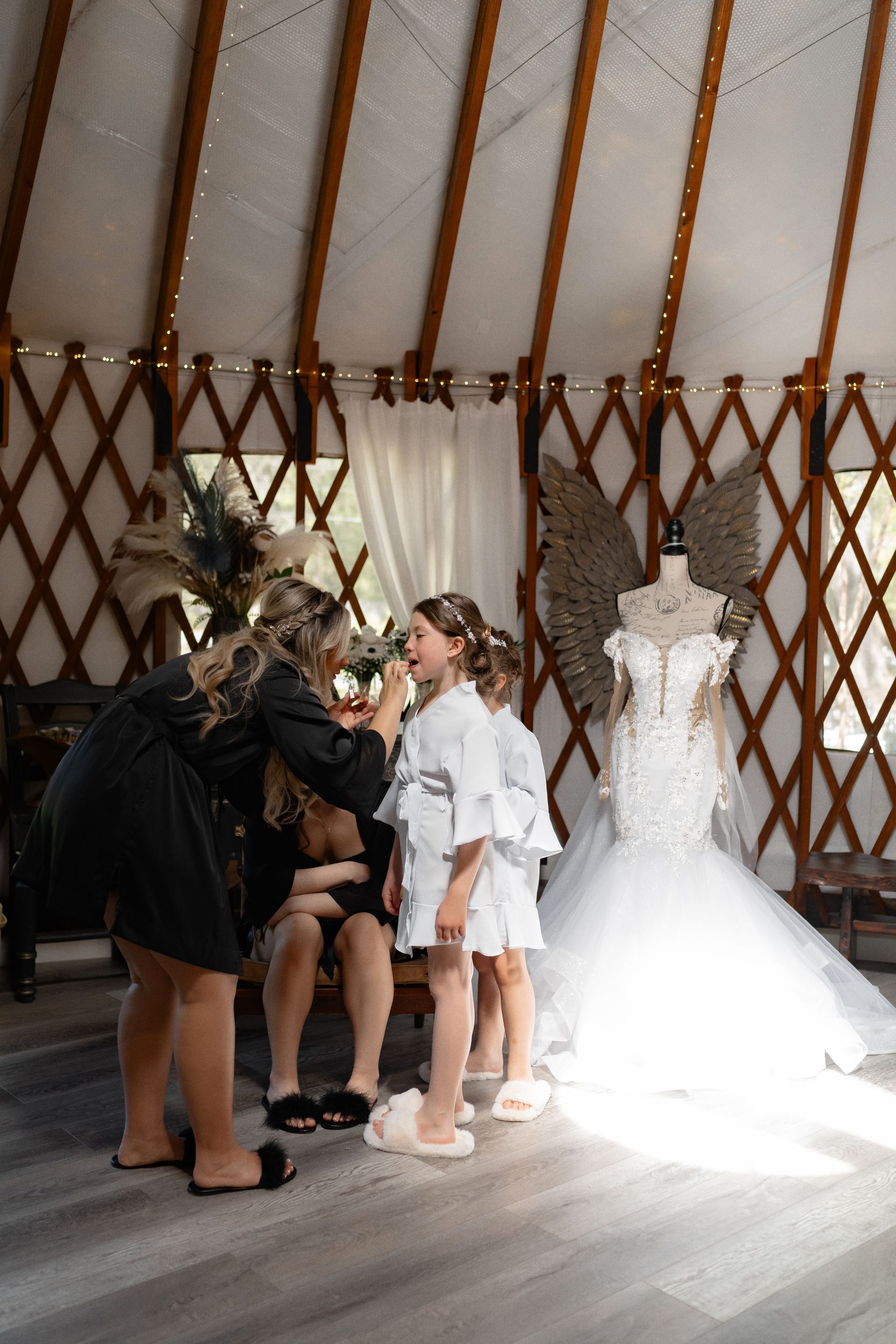 People gathered in a yurt beside a white wedding dress on a mannequin