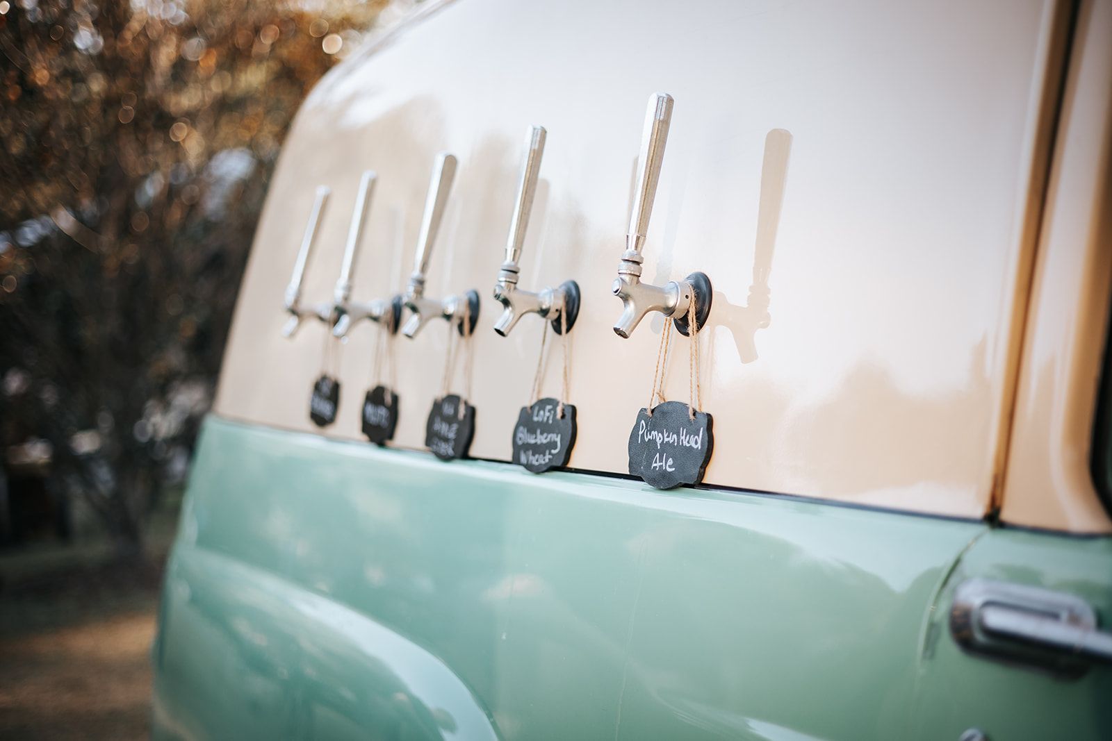 Vintage van side with several beer taps mounted on the exterior, in cream and mint green.