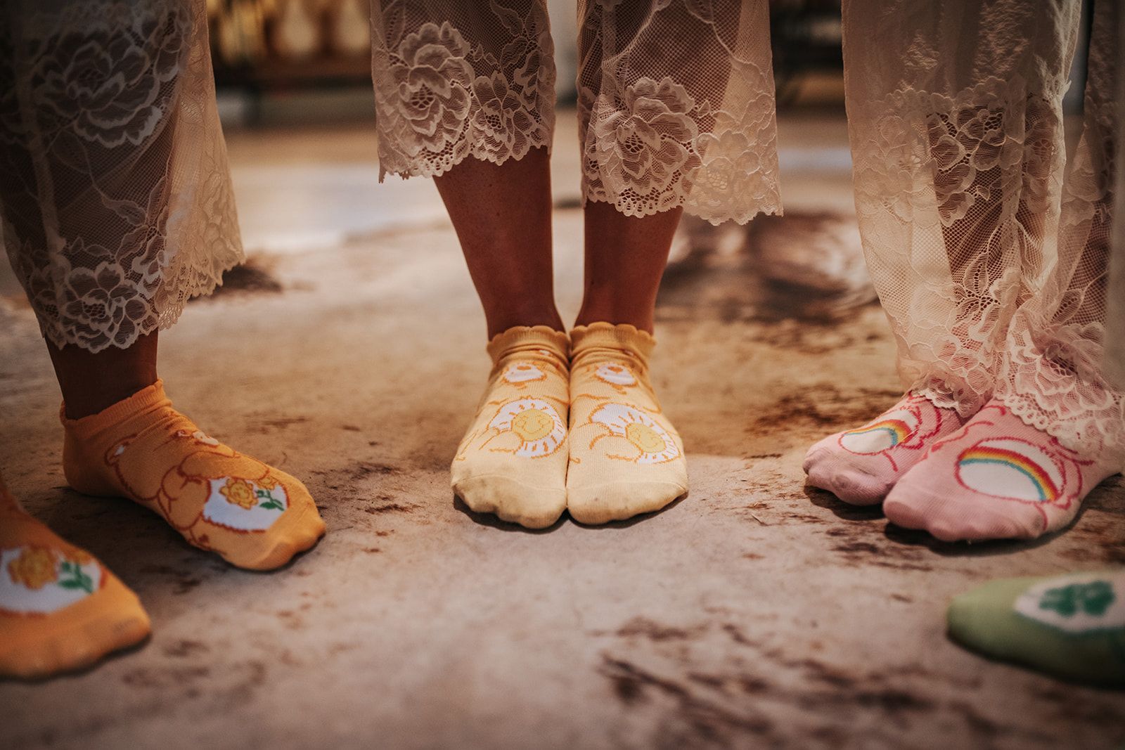 Children’s feet in lace dresses wearing colorful shoes on a dusty ground