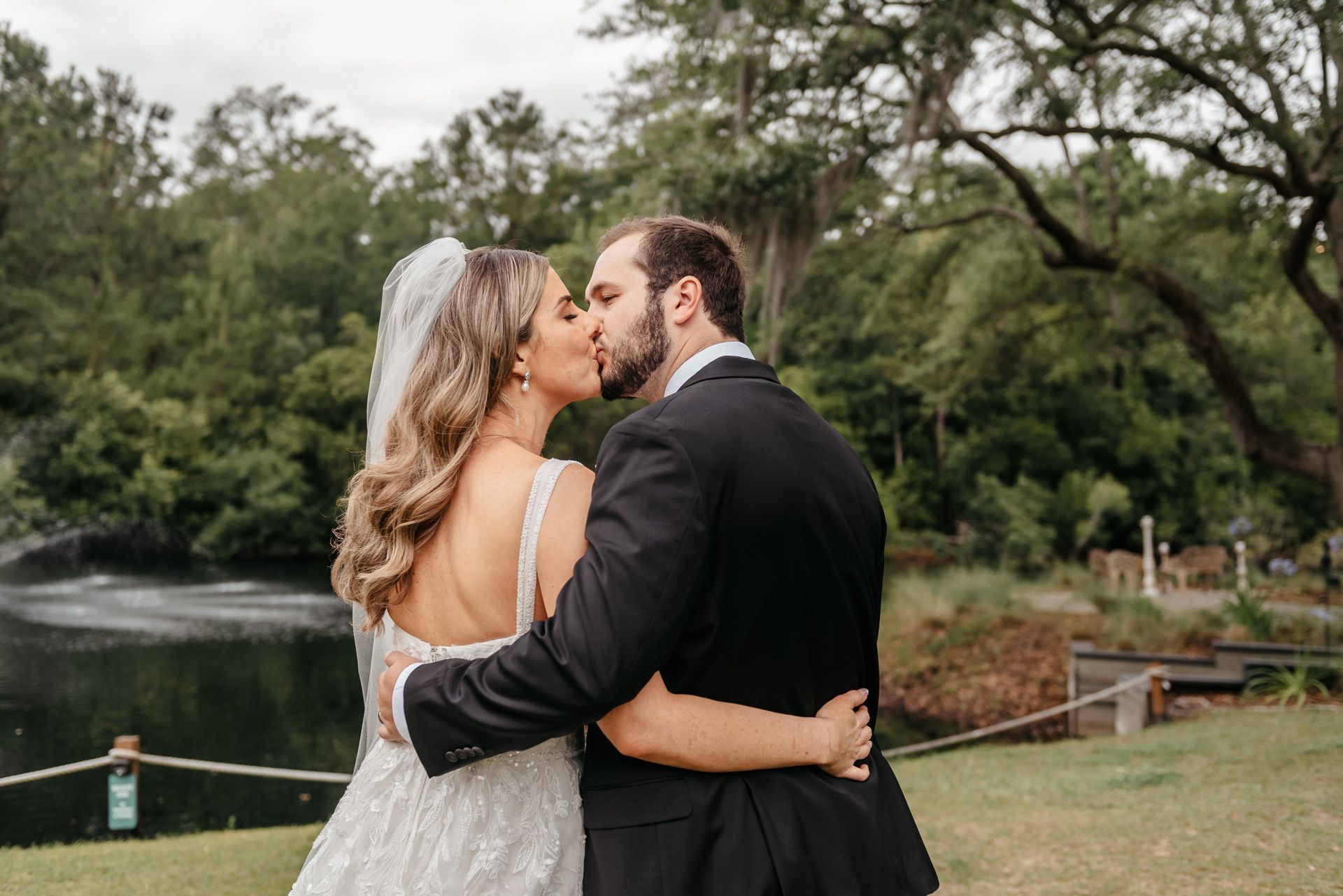 Couple embracing and kissing by a lakeside with trees in the background