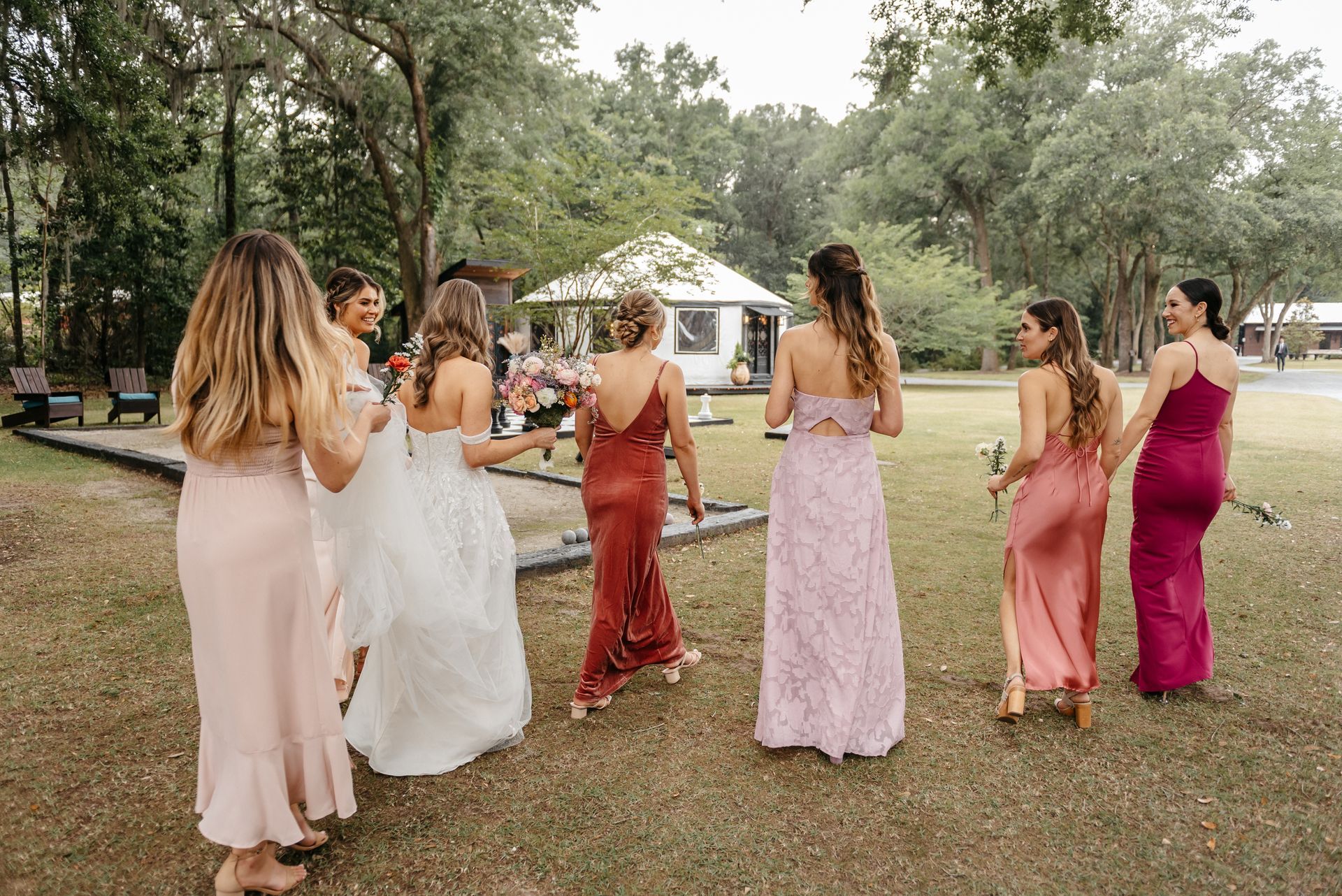 Women in pastel dresses walking together outdoors at a garden celebration
