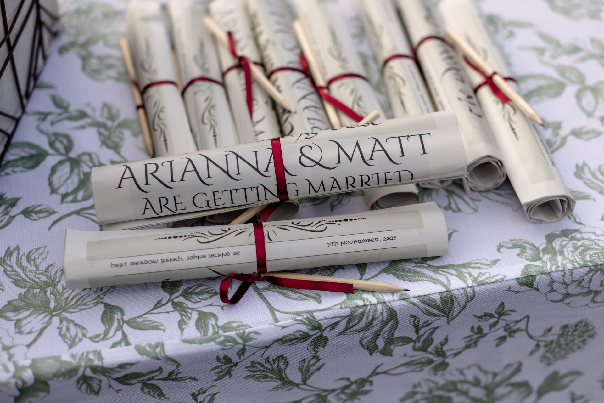 Stacks of rolled white papers tied with red ribbon on a floral tablecloth